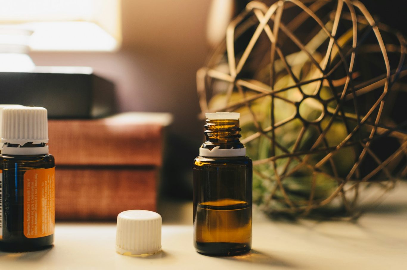 Two essential oil bottles and a decorative sphere on a wooden surface.